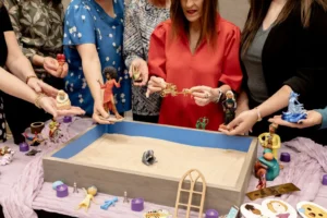 IAST board members leaning over a blue-rimmed sandtray, each holding out a figure