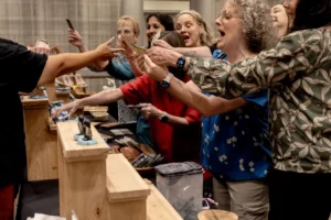 Sandtray Summit attendees reaching across a table to trade miniature figures
